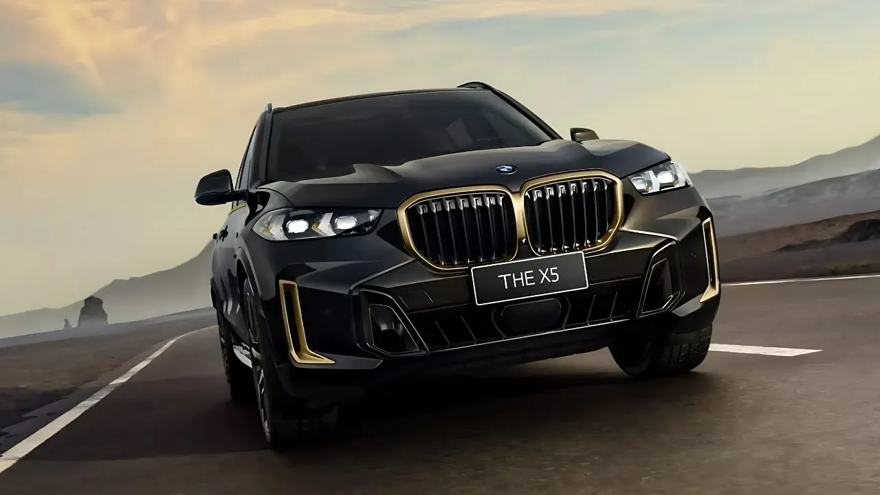 Juodas BMW X5 automobilis važiuoja keliu saulėlydžio fone.
